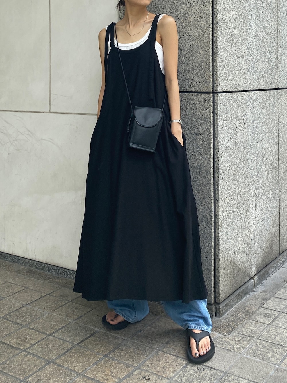 ブラック系のワンピース、ホワイト系のタンクトップ、ブルー系のデニムパンツを着用したレディースの夏コーディネートの2枚目の写真