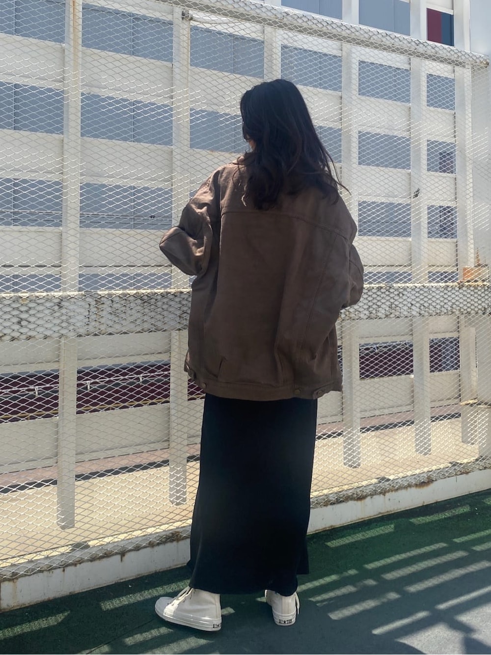 ブラウン系のデニムジャケット、ブラック系のスカート、ブラック系のキャミソールを着用したレディースの夏コーディネートの3枚目の写真