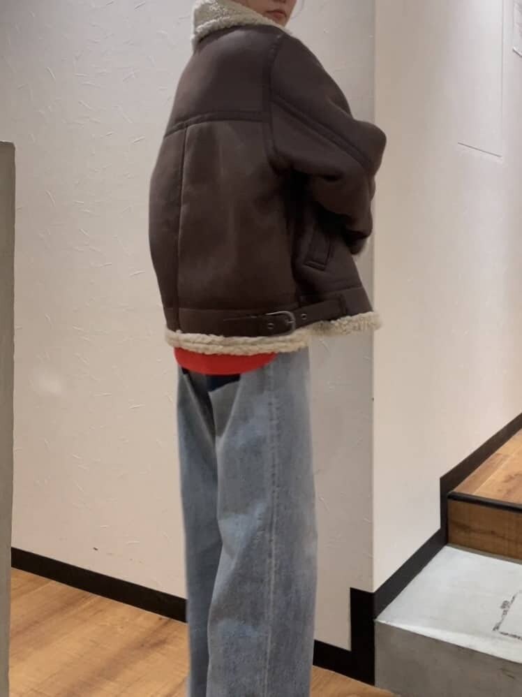 オレンジ系のニット/セーター、ブラウン系のムートンコート、ブルー系のデニムパンツを着用したレディースの秋コーディネートの3枚目の写真