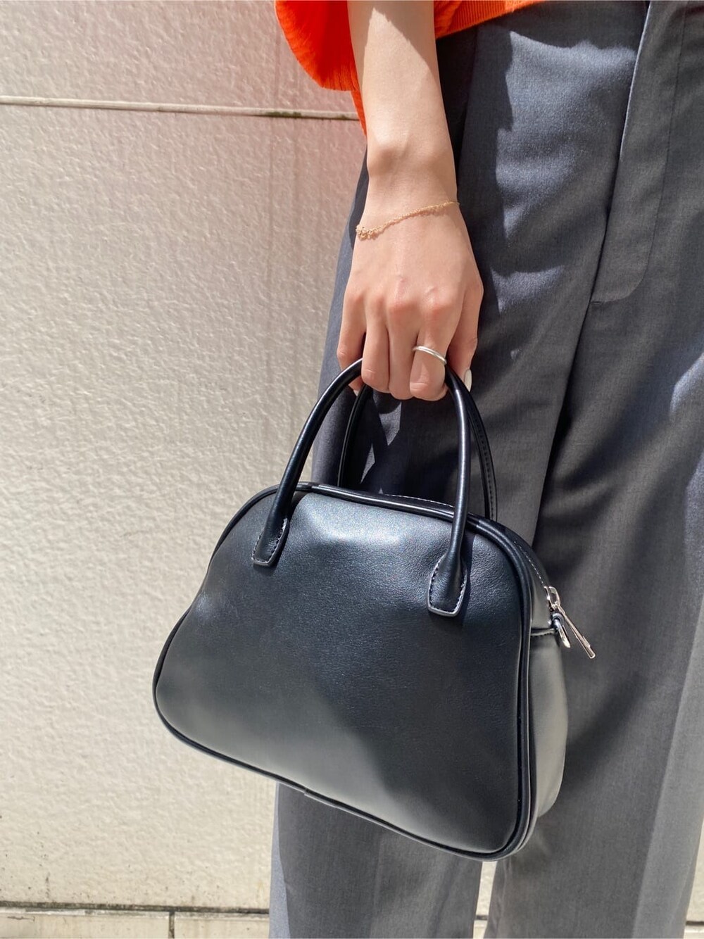 グレー系のその他パンツ、ブラック系のハンドバッグ、オレンジ系のカーディガン/ボレロを着用したレディースの春コーディネートの7枚目の写真