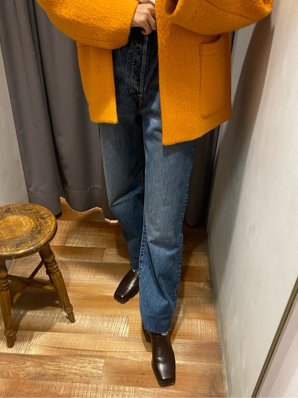 イエロー系のテーラードジャケット、ブラウン系のブーツ、ブルー系のデニムパンツを着用したレディースの秋コーディネートの4枚目の写真