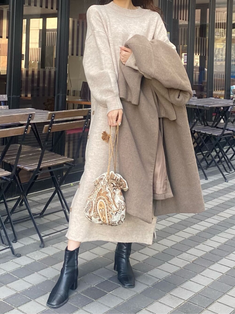 ベージュ系のチェスターコート、ホワイト系のハンドバッグ、グレー系のワンピースを着用したレディースの秋コーディネートの4枚目の写真