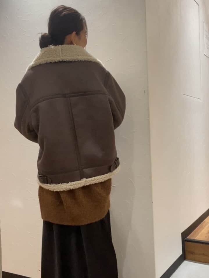 ブラック系のスカート、ブラウン系のムートンコート、ブラウン系のカーディガン/ボレロを着用したレディースの秋コーディネートの3枚目の写真