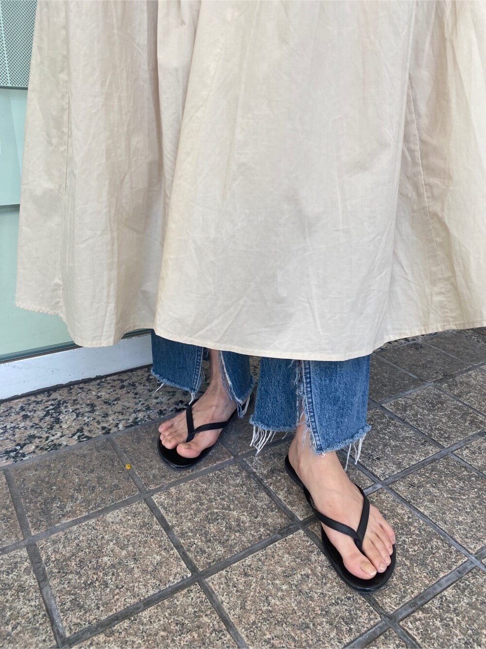 ブルー系のデニムパンツ、ベージュ系のワンピースを着用したレディースの春コーディネートの5枚目の写真