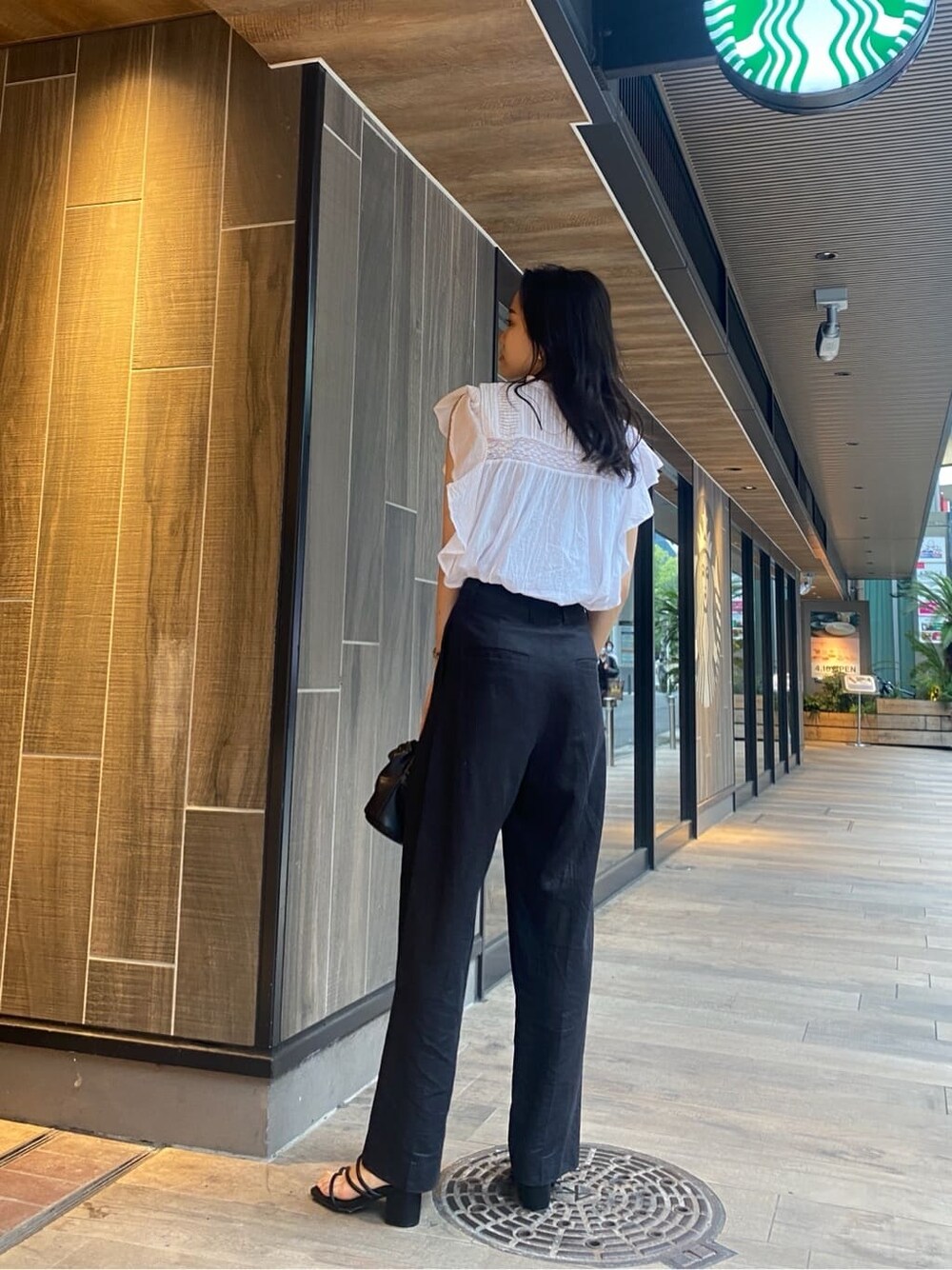 ブラック系のサンダル、ブラック系のその他パンツ、ホワイト系のシャツ/ブラウスを着用したレディースの春コーディネートの2枚目の写真