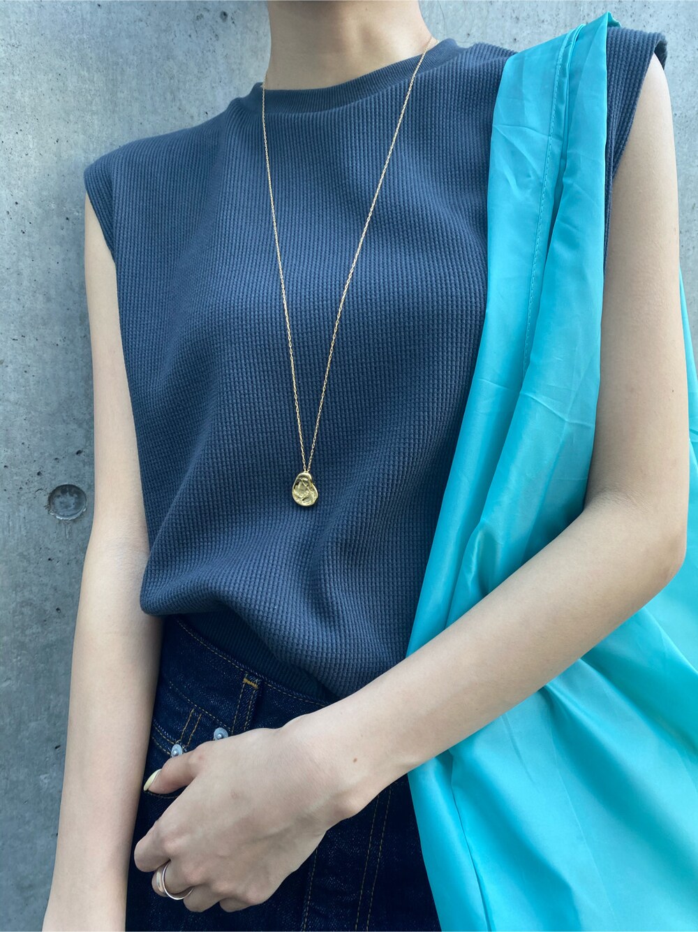 ブルー系のハンドバッグ、ブルー系のデニムパンツ、グレー系のタンクトップを着用したレディースの春コーディネートの4枚目の写真