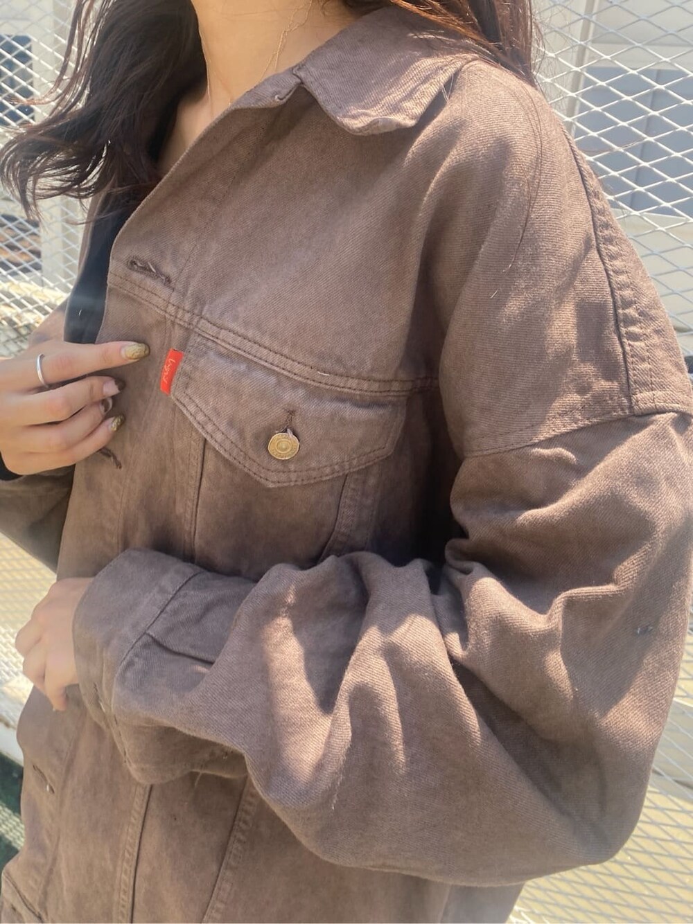 ブラウン系のデニムジャケット、ブラック系のスカート、ブラック系のキャミソールを着用したレディースの夏コーディネートの5枚目の写真