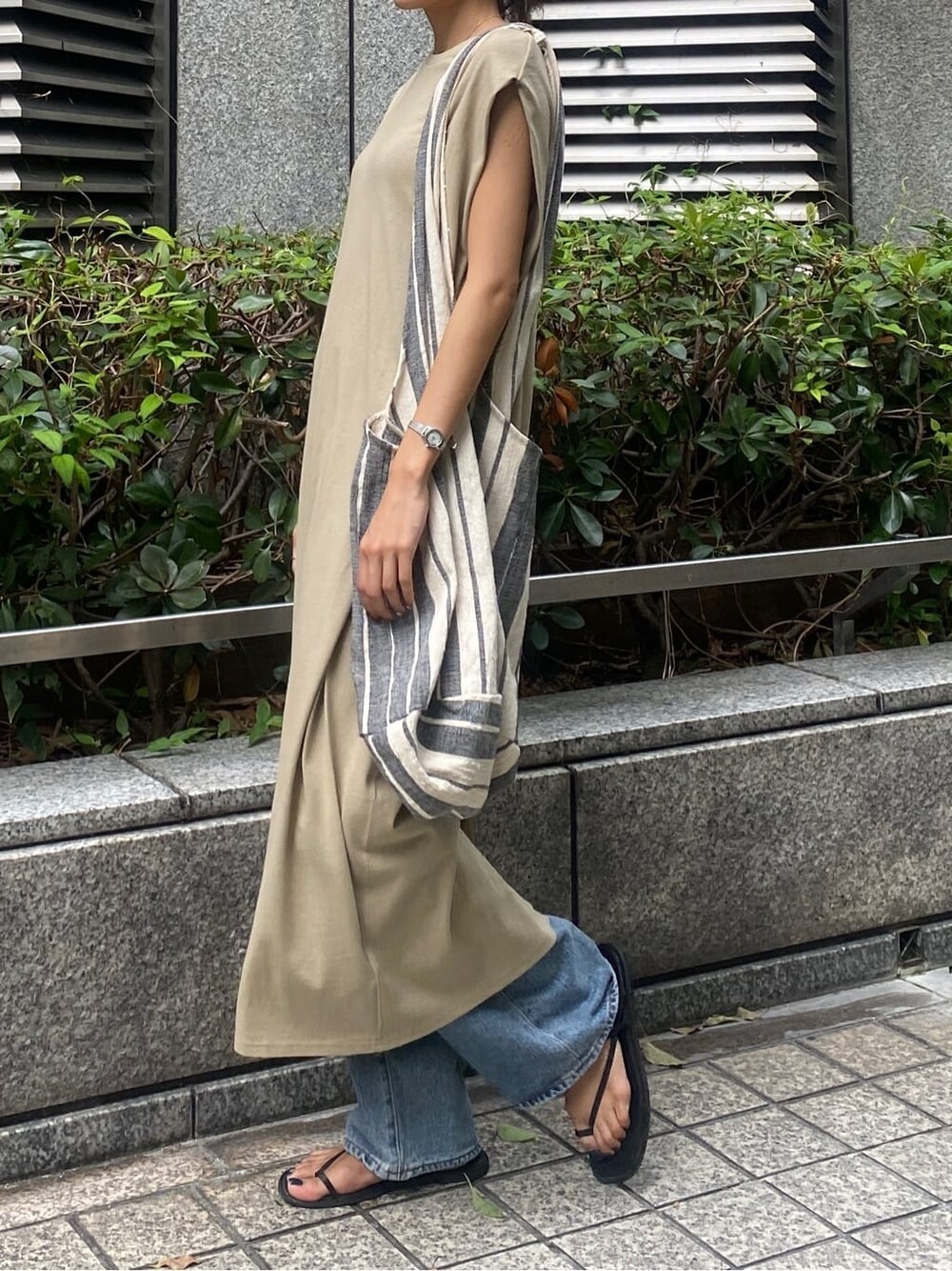 ブラック系のサンダル、ベージュ系のワンピース、ブルー系のデニムパンツを着用したレディースの夏コーディネートの3枚目の写真