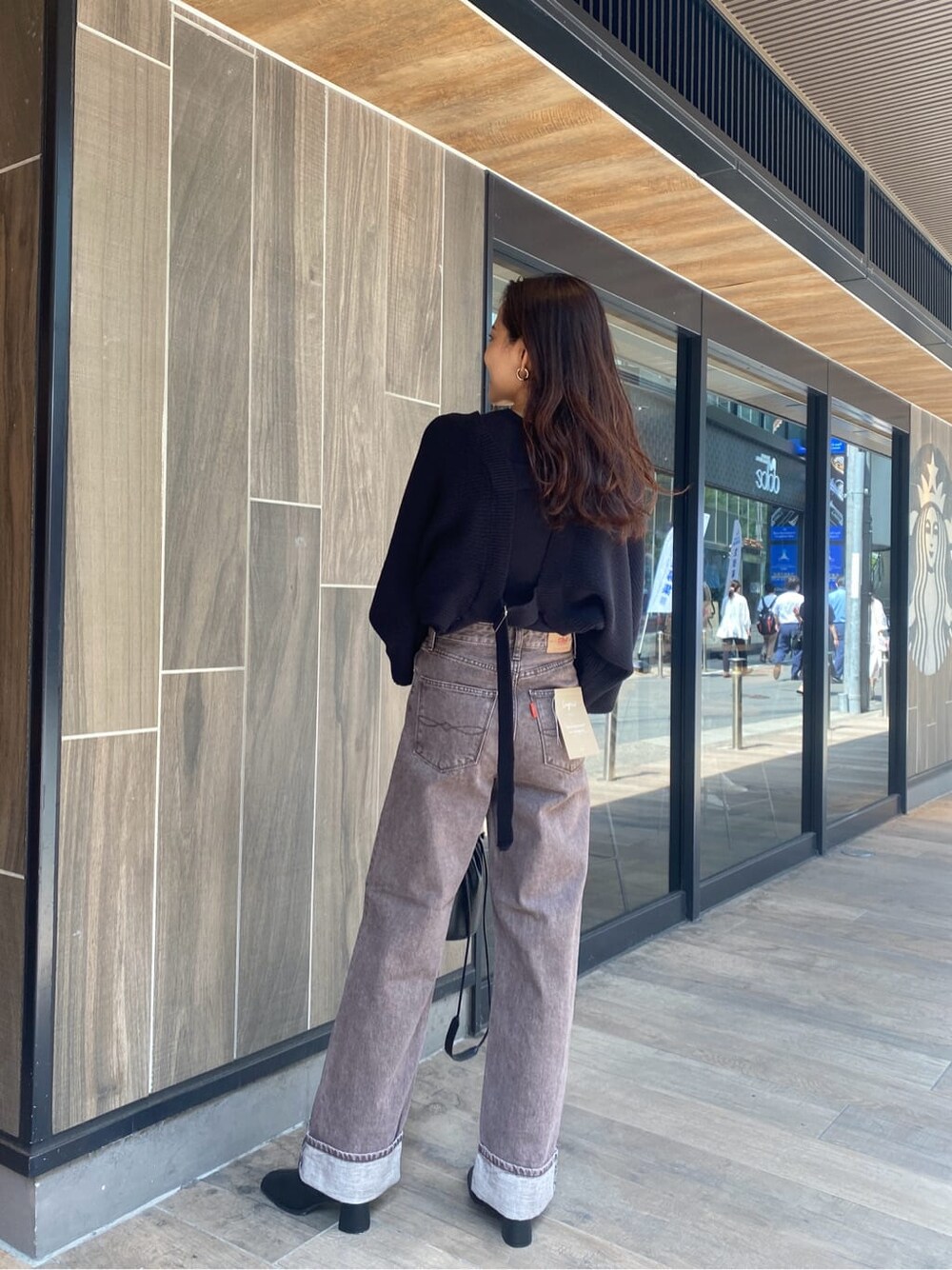 ブラック系のブーツ、ブラウン系のデニムパンツ、ブラック系のカーディガン/ボレロを着用したレディースの秋コーディネートの3枚目の写真