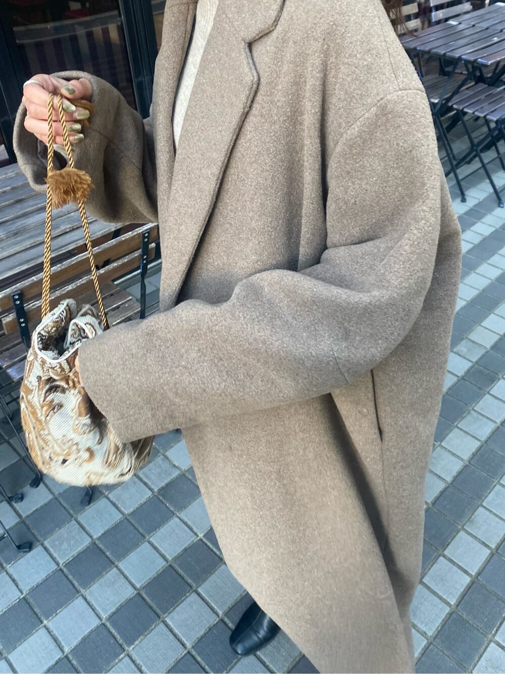 ベージュ系のチェスターコート、ホワイト系のハンドバッグ、グレー系のワンピースを着用したレディースの秋コーディネートの7枚目の写真