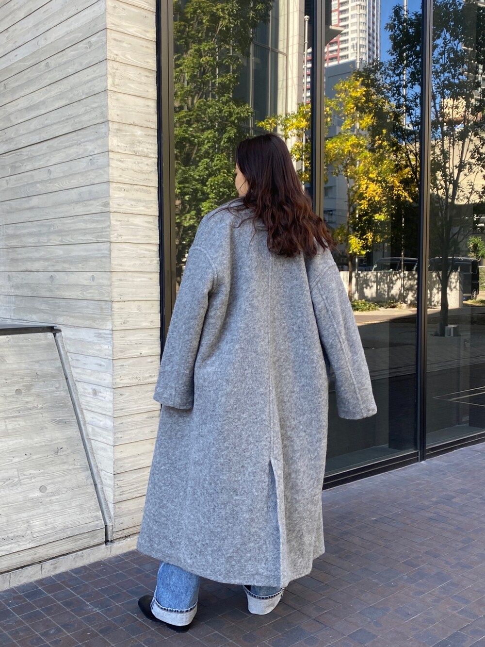 ホワイト系のニット/セーター、グレー系のチェスターコート、ブルー系のデニムパンツを着用したレディースの秋コーディネートの3枚目の写真