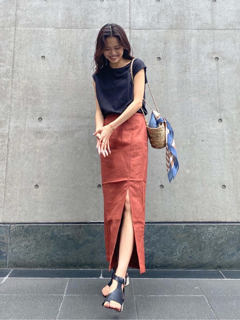 ベージュ系のかごバッグ、ブラック系のタンクトップ、オレンジ系のスカートを着用したレディースの夏コーディネートの2枚目の写真