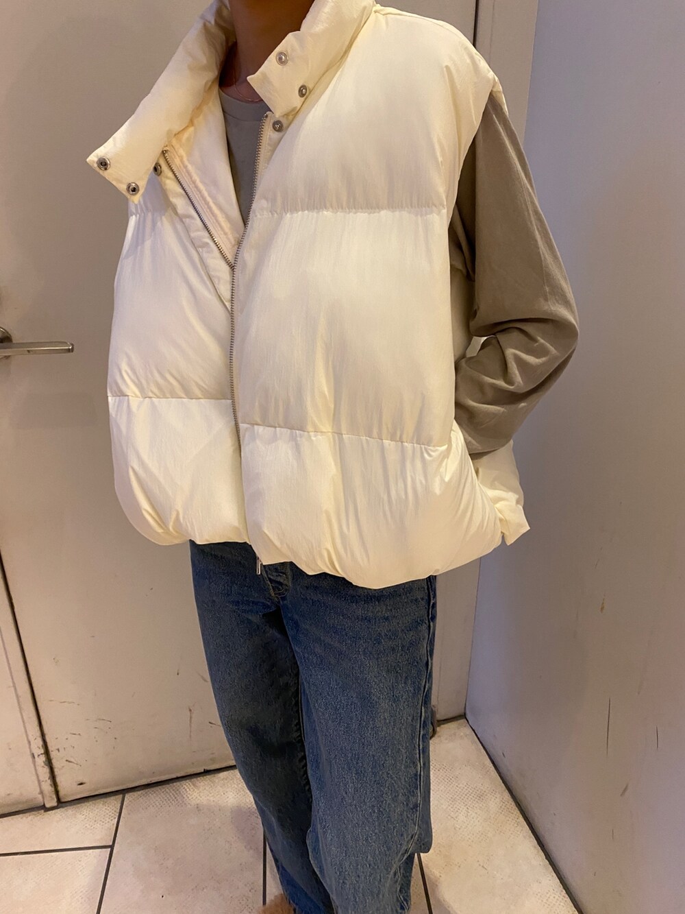 ブルー系のデニムパンツ、グレー系のTシャツ/カットソー、ホワイト系のダウンベストを着用したレディースの秋コーディネートの3枚目の写真
