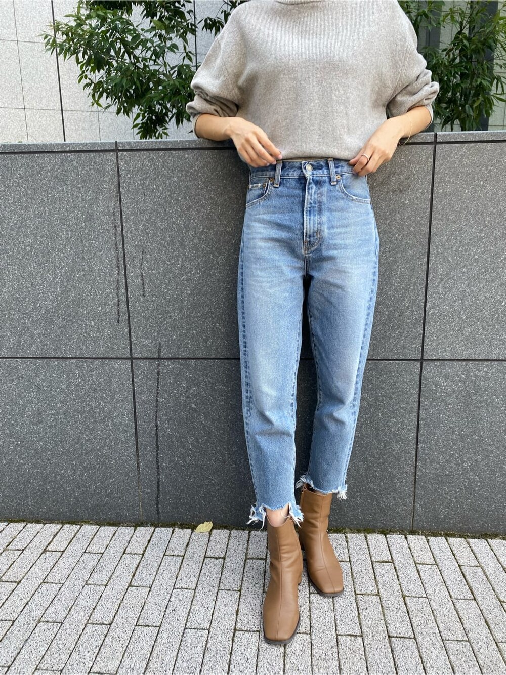 ブラック系のチェスターコート、ブルー系のデニムパンツ、グレー系のニット/セーターを着用したレディースの秋コーディネートの6枚目の写真