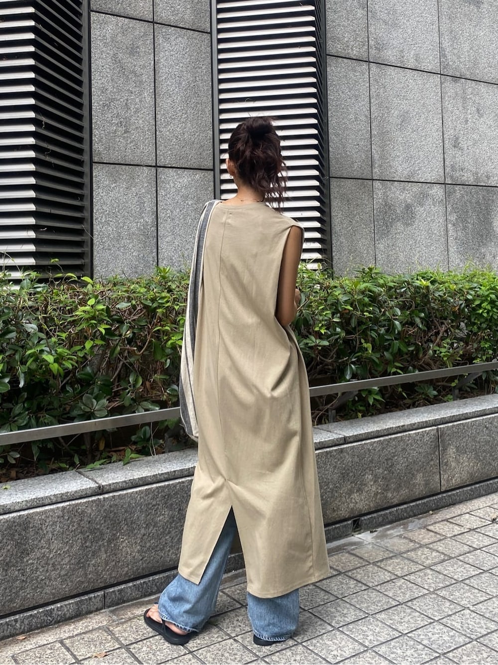 ブラック系のサンダル、ベージュ系のワンピース、ブルー系のデニムパンツを着用したレディースの夏コーディネートの2枚目の写真