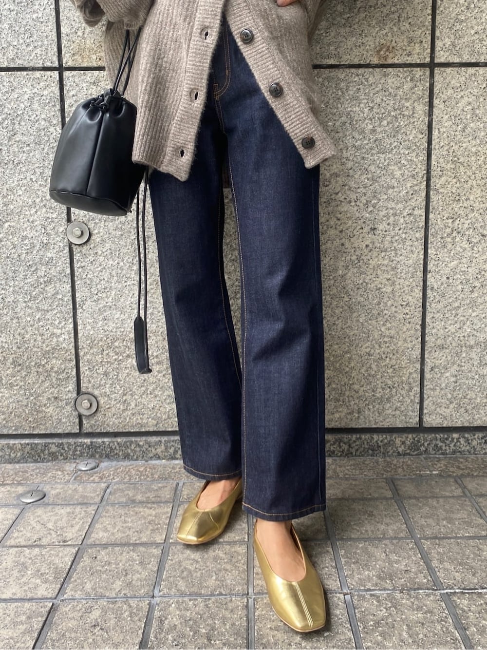 ゴールド系のパンプス、ブラック系のハンドバッグ、ブルー系のデニムパンツを着用したレディースの秋コーディネートの7枚目の写真