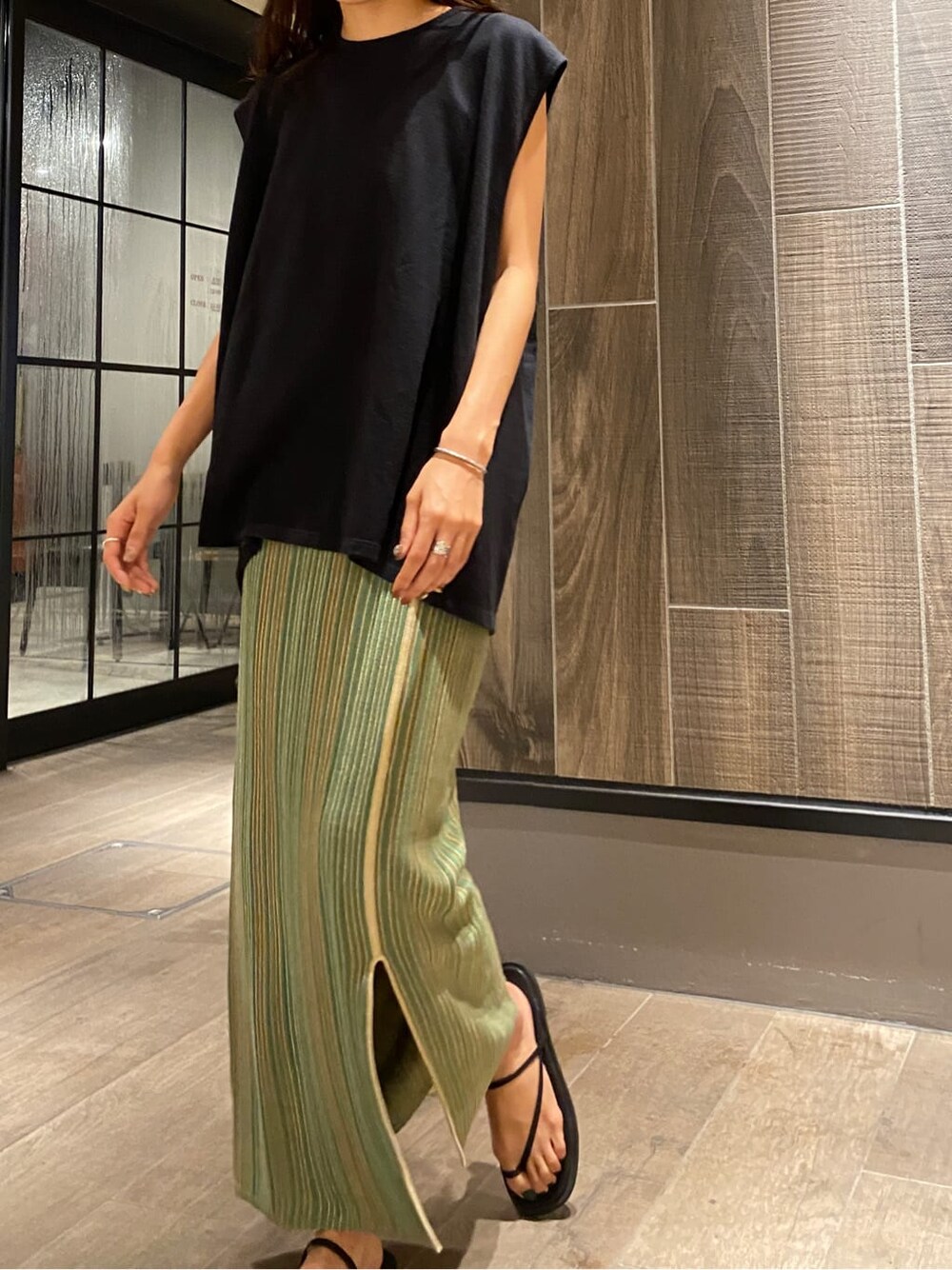 ブラック系のサンダル、ブラック系のTシャツ/カットソー、グリーン系のスカートを着用したレディースの夏コーディネートの5枚目の写真