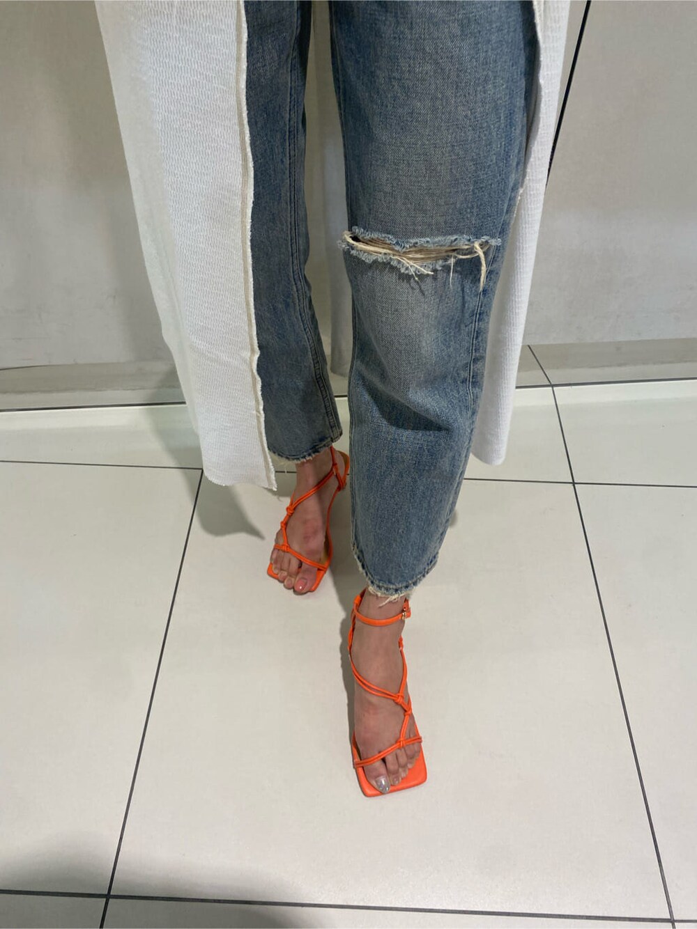 ブルー系のデニムパンツ、オレンジ系のサンダル、ホワイト系のワンピースを着用したレディースの夏コーディネートの5枚目の写真