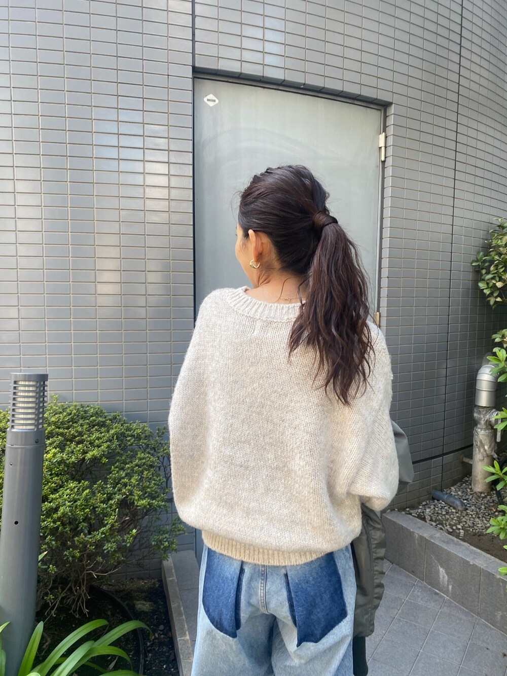 ホワイト系のニット/セーター、ブルー系のデニムパンツ、ブラック系のブーツを着用したレディースの秋コーディネートの6枚目の写真