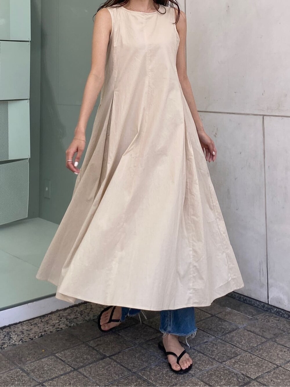 ブルー系のデニムパンツ、ベージュ系のワンピースを着用したレディースの春コーディネートの3枚目の写真