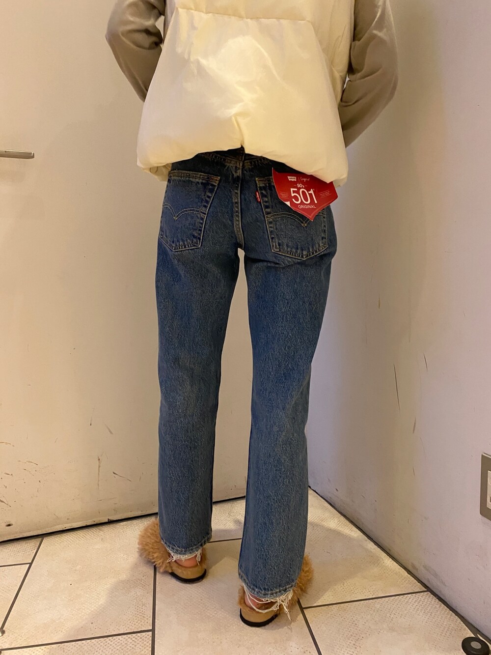 ブルー系のデニムパンツ、グレー系のTシャツ/カットソー、ホワイト系のダウンベストを着用したレディースの秋コーディネートの6枚目の写真