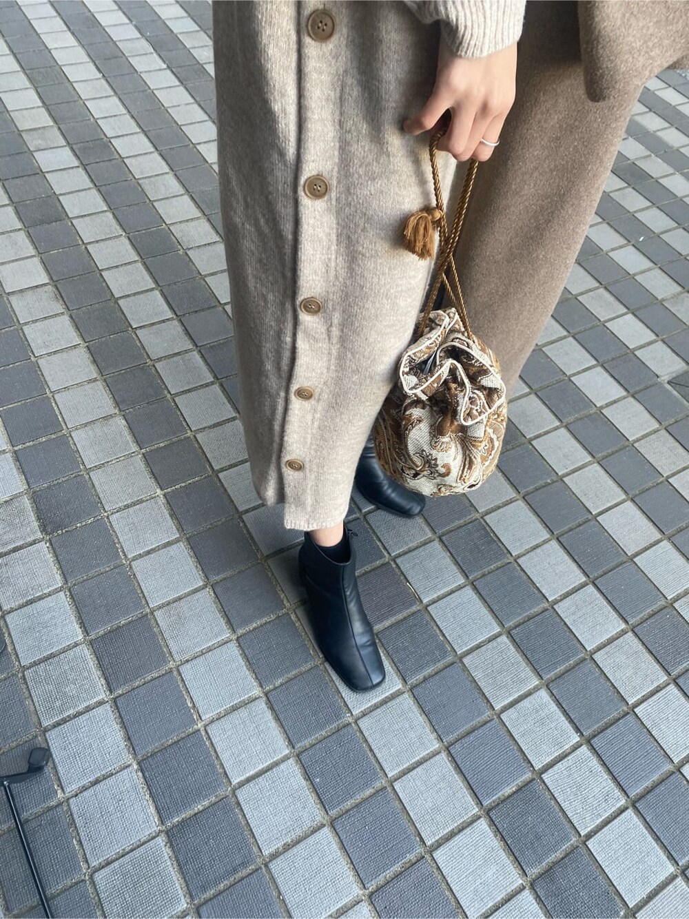 ベージュ系のチェスターコート、ホワイト系のハンドバッグ、グレー系のワンピースを着用したレディースの秋コーディネートの5枚目の写真