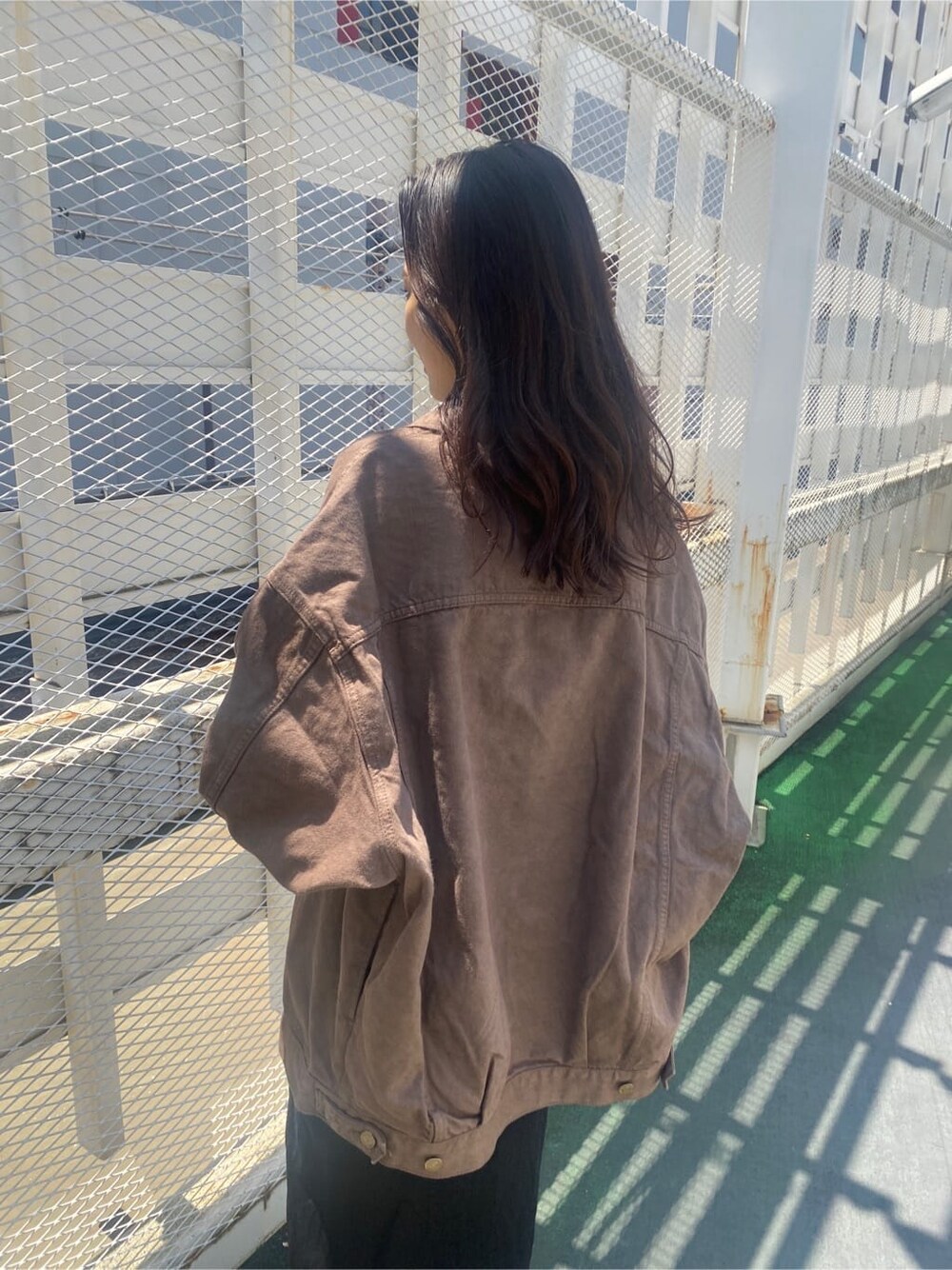 ブラウン系のデニムジャケット、ブラック系のスカート、ブラック系のキャミソールを着用したレディースの夏コーディネートの6枚目の写真