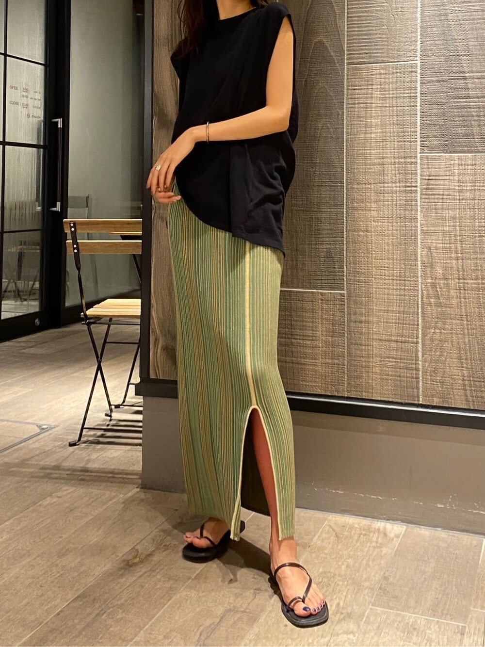 ブラック系のサンダル、ブラック系のTシャツ/カットソー、グリーン系のスカートを着用したレディースの夏コーディネートの2枚目の写真