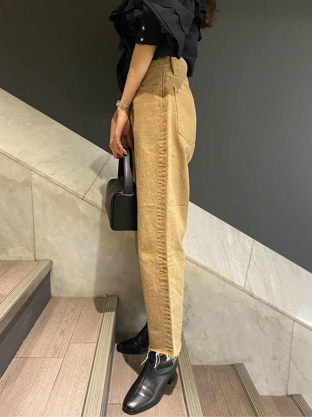 ブラック系のシャツ/ブラウス、ブラック系のハンドバッグ、ベージュ系のデニムパンツを着用したレディースの冬コーディネートの5枚目の写真