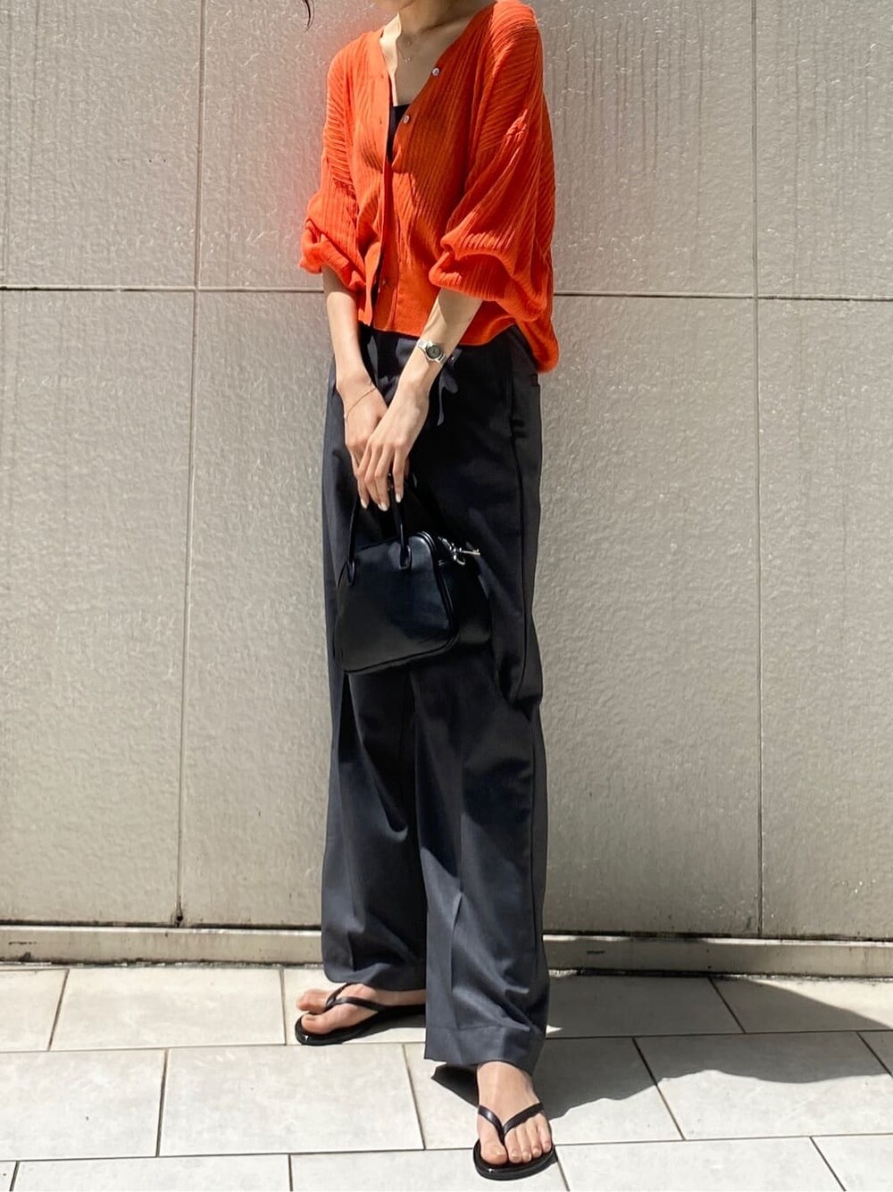 グレー系のその他パンツ、ブラック系のハンドバッグ、オレンジ系のカーディガン/ボレロを着用したレディースの春コーディネートの3枚目の写真