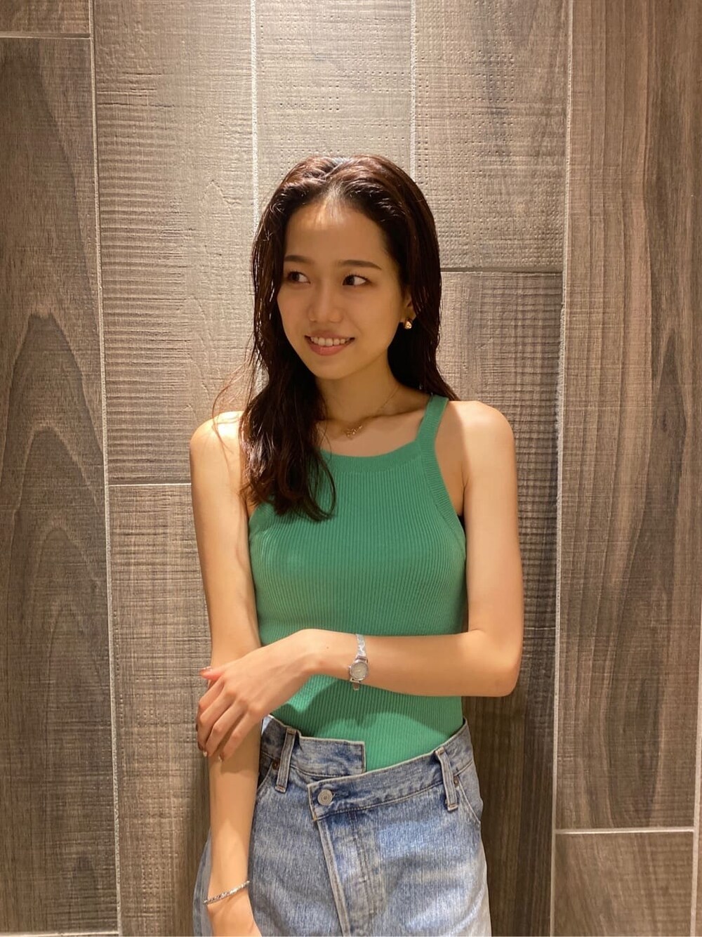 グリーン系のタンクトップ、ブルー系のデニムパンツを着用したレディースの夏コーディネートの4枚目の写真