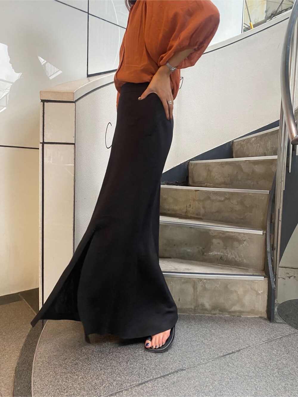 ブラック系のサンダル、オレンジ系のシャツ/ブラウス、ブラック系のスカートを着用したレディースの夏コーディネートの8枚目の写真