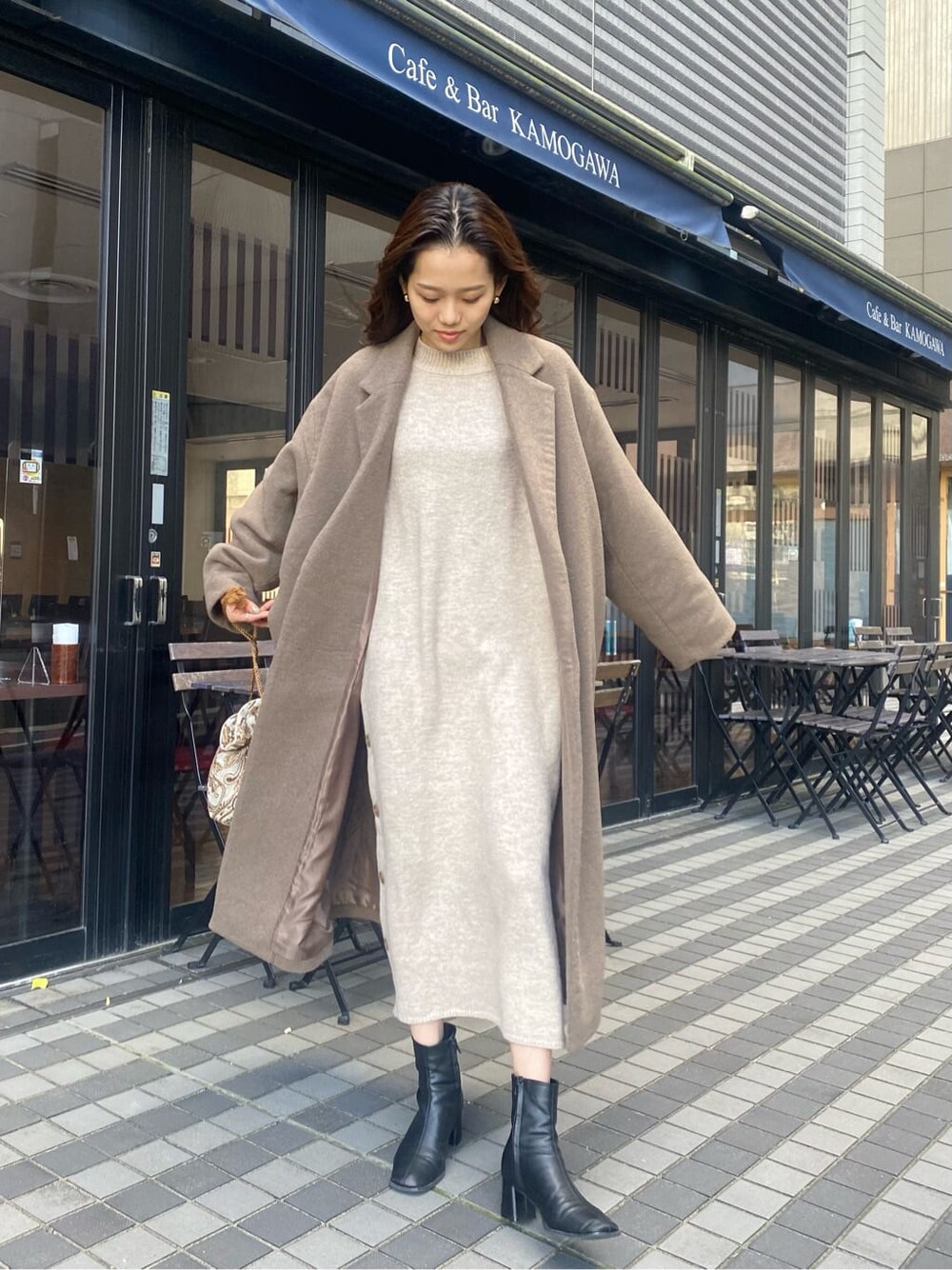 ベージュ系のチェスターコート、ホワイト系のハンドバッグ、グレー系のワンピースを着用したレディースの秋コーディネートの2枚目の写真