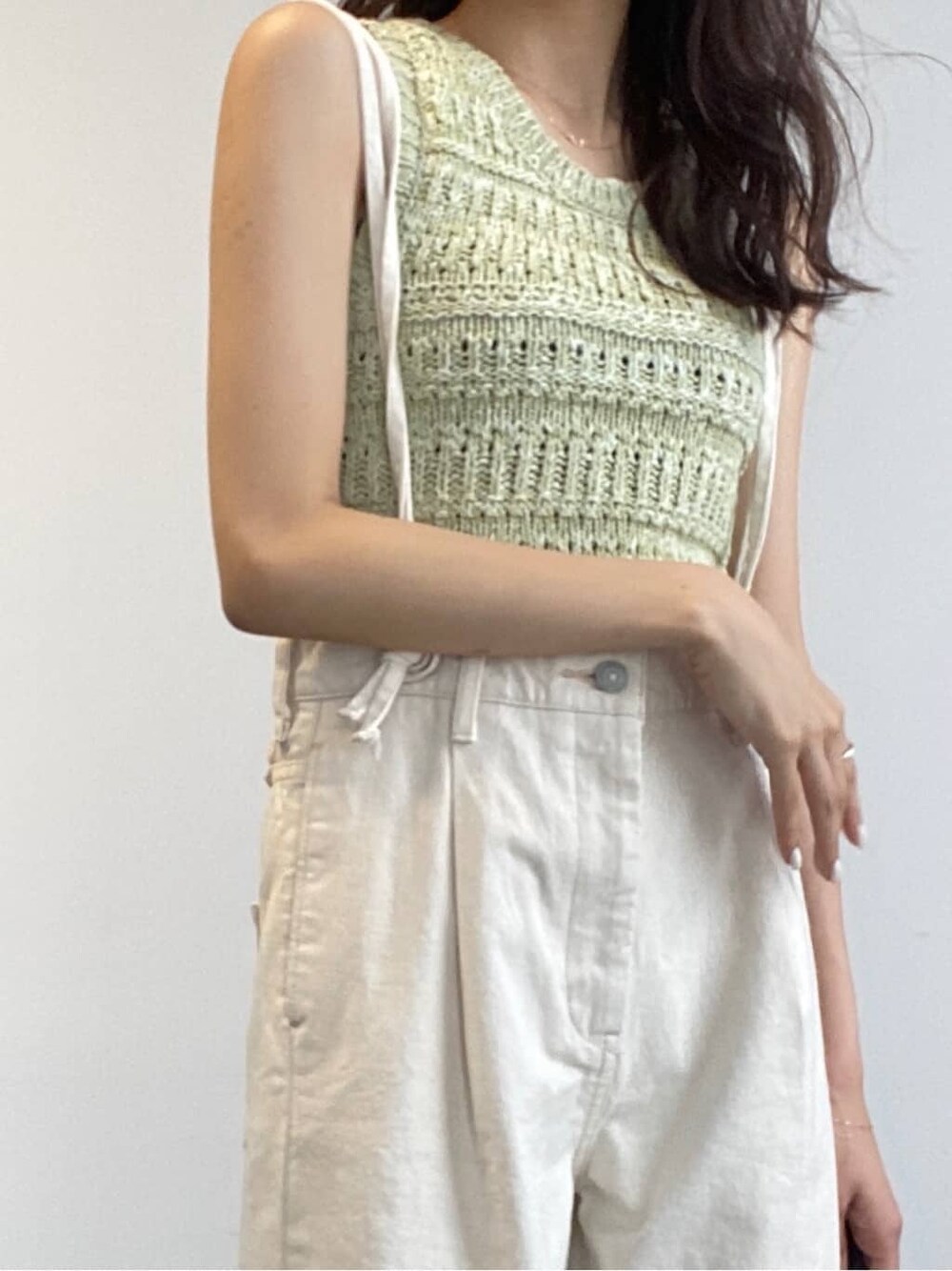 ホワイト系のデニムパンツ、グリーン系のニット/セーターを着用したレディースの春コーディネートの5枚目の写真