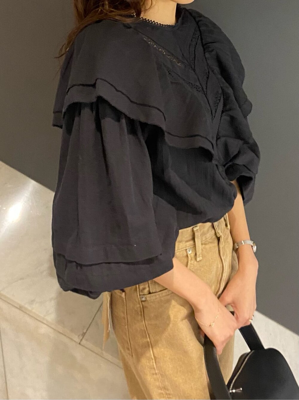 ブラック系のシャツ/ブラウス、ブラック系のハンドバッグ、ベージュ系のデニムパンツを着用したレディースの冬コーディネートの8枚目の写真