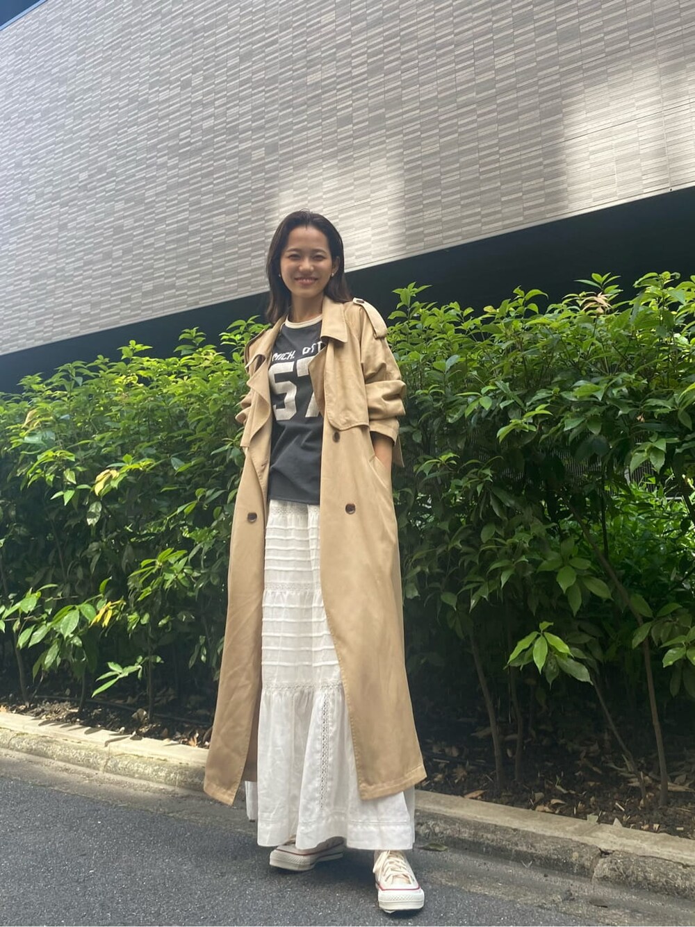 ベージュ系のトレンチコート、ホワイト系のスカート、グレー系のTシャツ/カットソーを着用したレディースの夏コーディネートの2枚目の写真