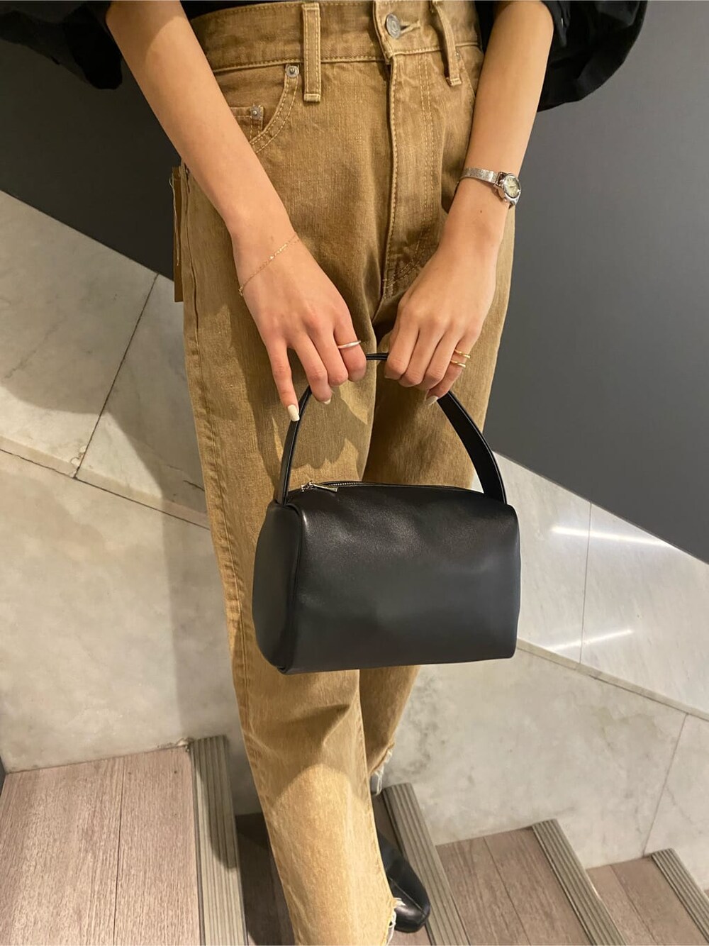 ブラック系のシャツ/ブラウス、ブラック系のハンドバッグ、ベージュ系のデニムパンツを着用したレディースの冬コーディネートの6枚目の写真