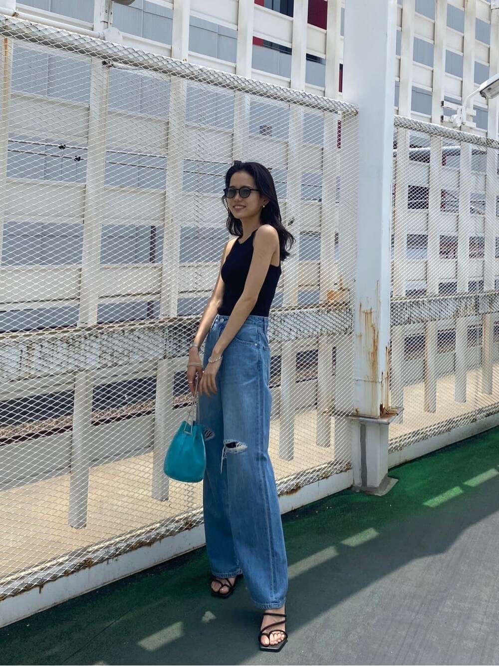 ブラック系のサンダル、ブルー系のハンドバッグ、ブラック系のタンクトップを着用したレディースの夏コーディネートの2枚目の写真