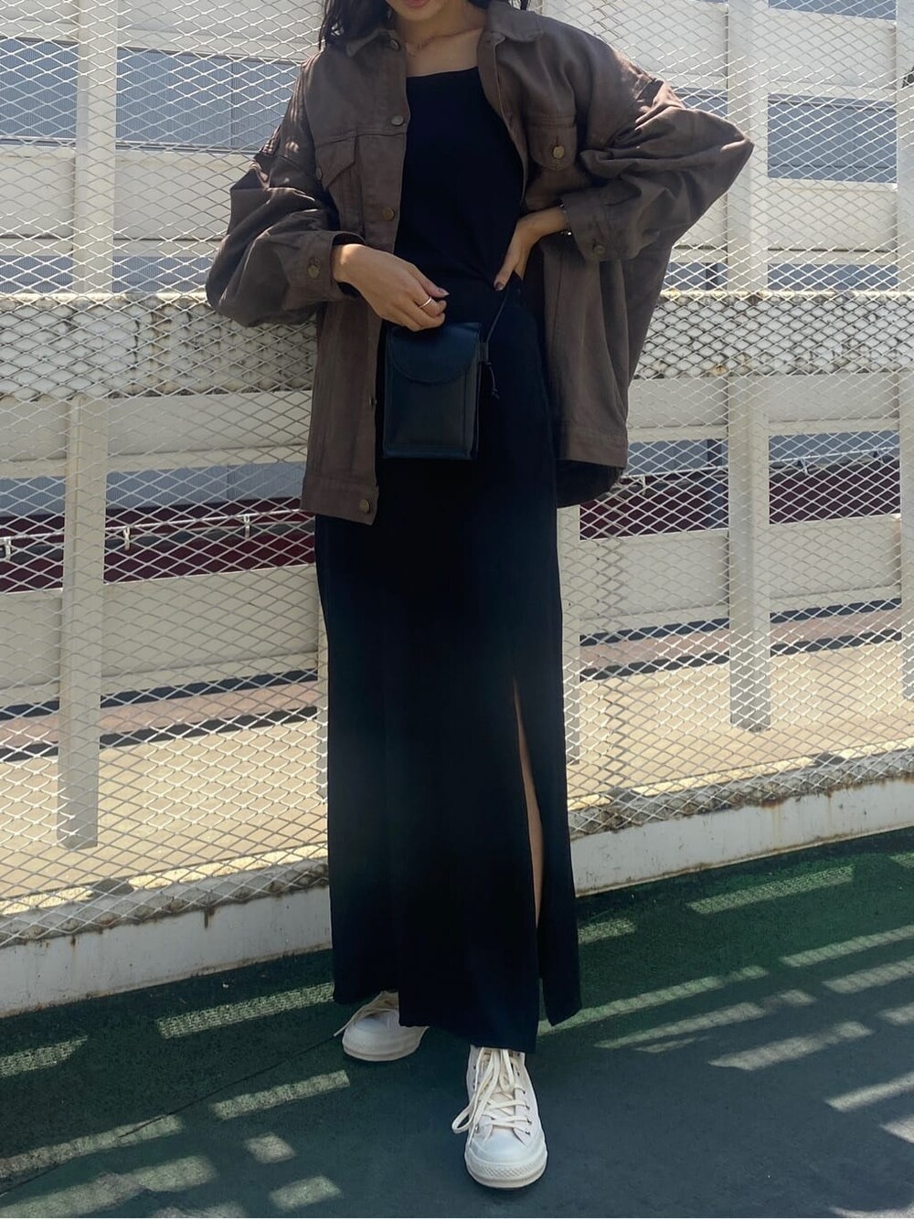 ブラウン系のデニムジャケット、ブラック系のスカート、ブラック系のキャミソールを着用したレディースの夏コーディネートの2枚目の写真