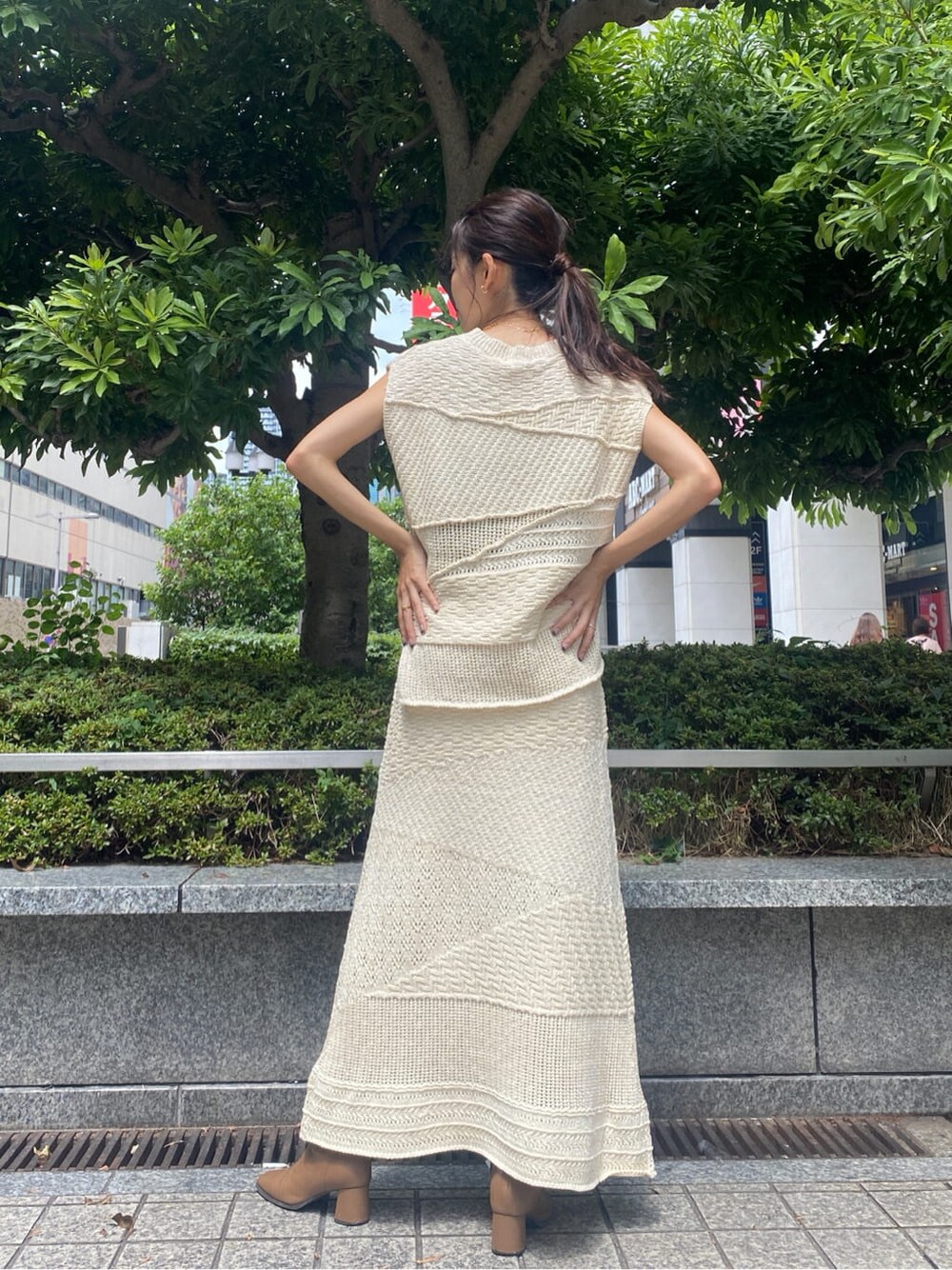 ホワイト系のスカート、ホワイト系のニット/セーター、ゴールド系のネックレスを着用したレディースの夏コーディネートの3枚目の写真