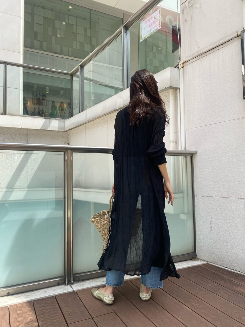 ブルー系のデニムパンツ、ブラック系のワンピース、ベージュ系のかごバッグを着用したレディースの春コーディネートの3枚目の写真