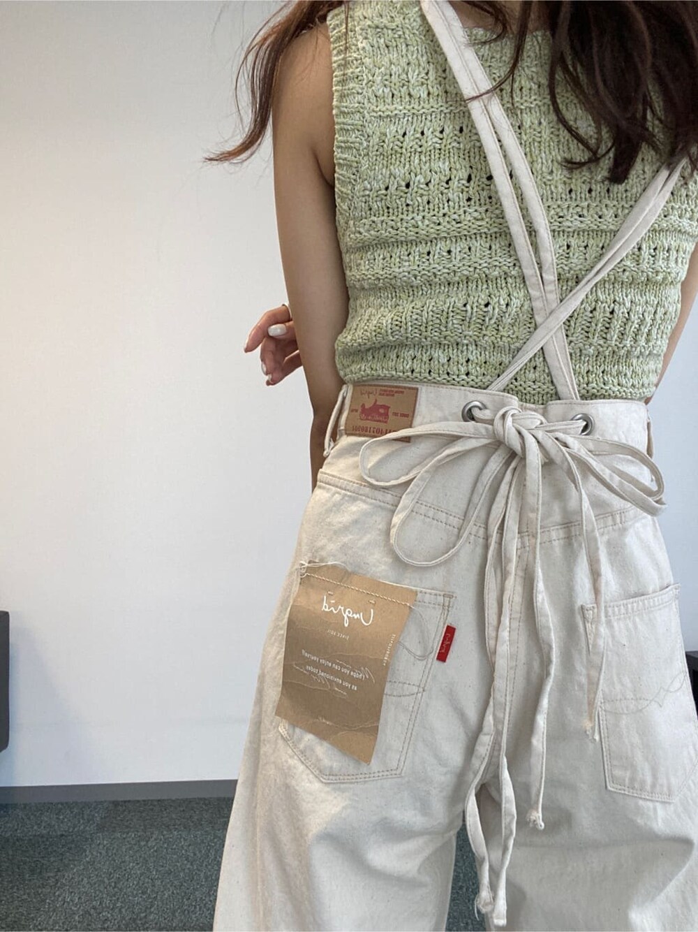 ホワイト系のデニムパンツ、グリーン系のニット/セーターを着用したレディースの春コーディネートの6枚目の写真