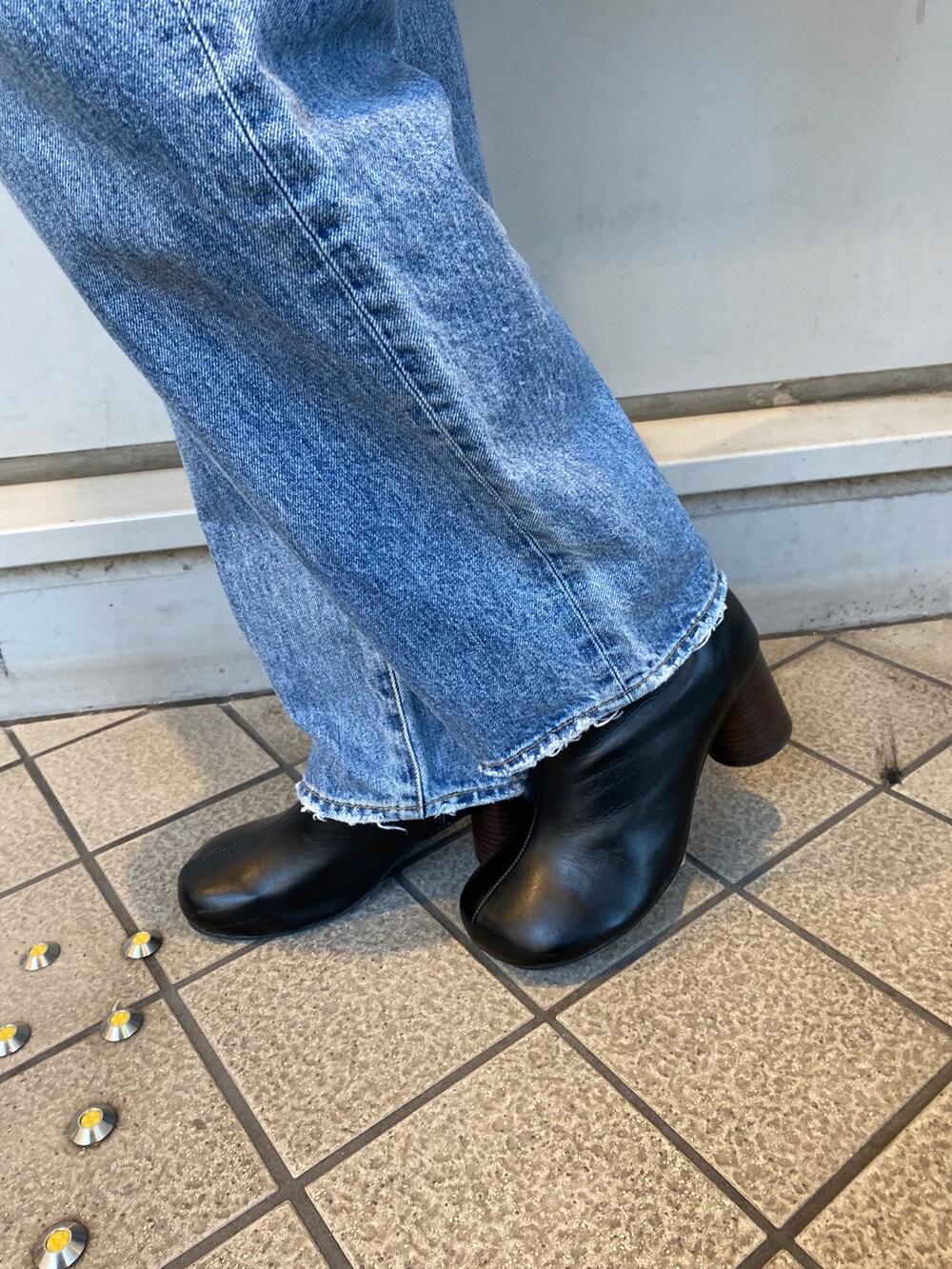 グレー系のニット/セーター、ブルー系のデニムパンツ、ブラック系のブーツを着用したレディースの秋コーディネートの5枚目の写真