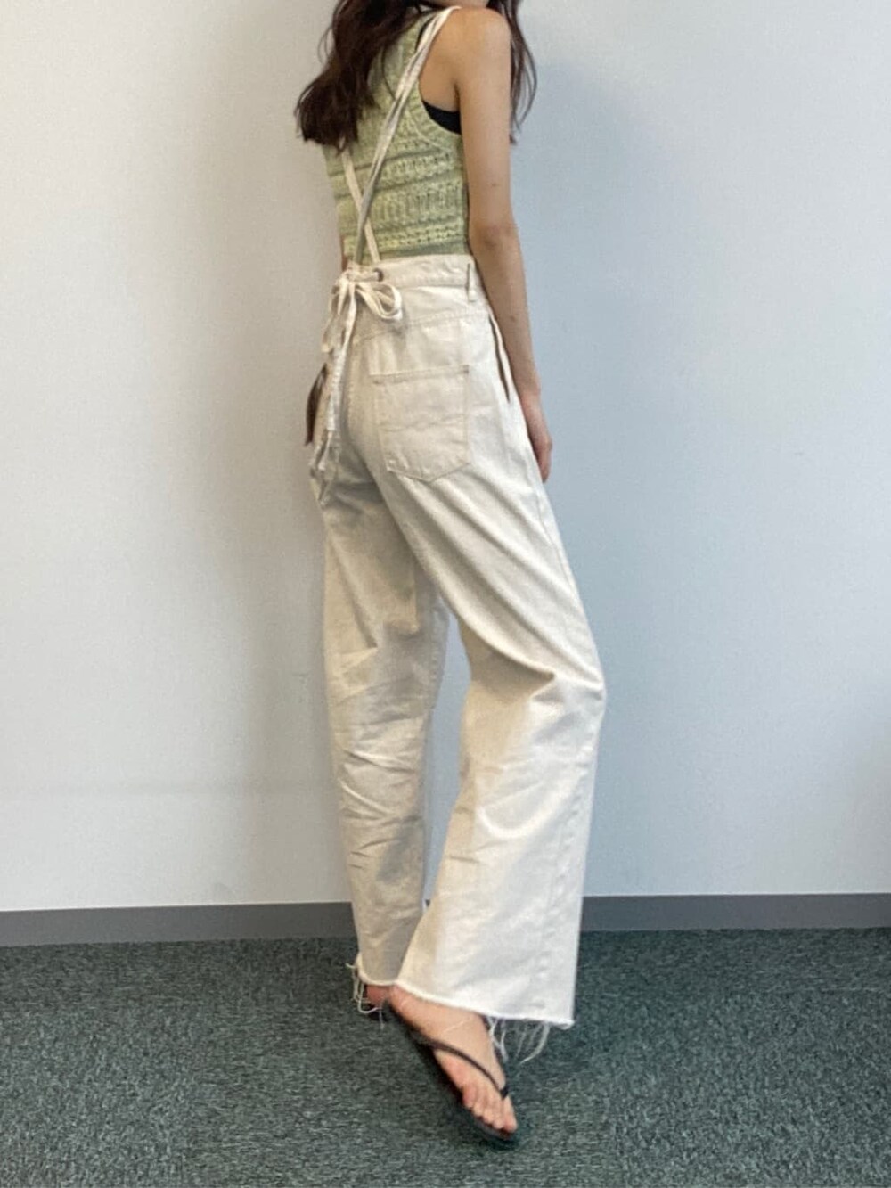 ホワイト系のデニムパンツ、グリーン系のニット/セーターを着用したレディースの春コーディネートの2枚目の写真