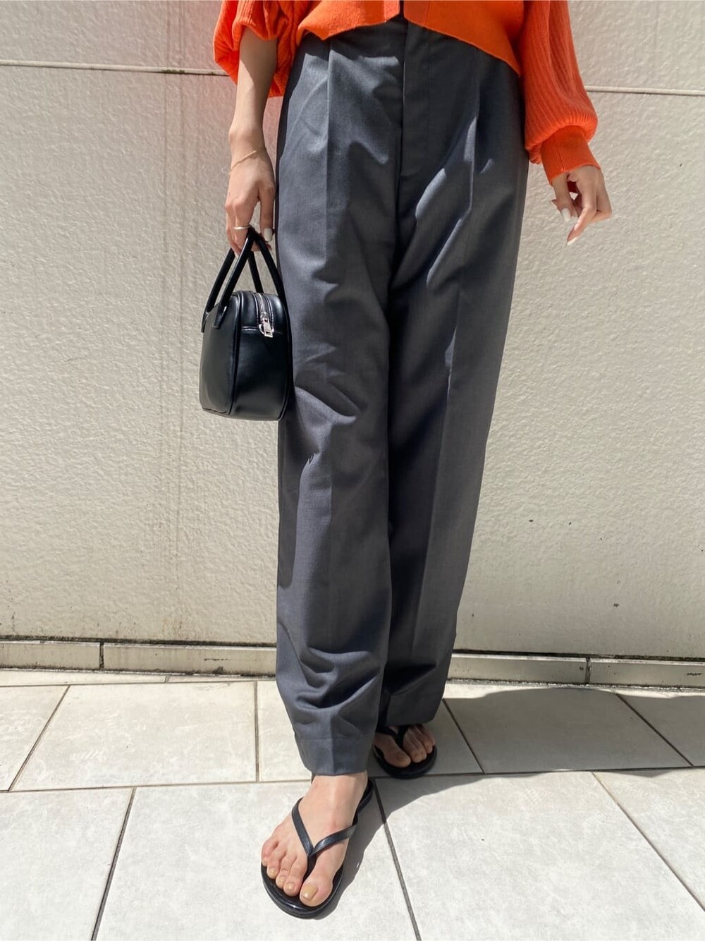 グレー系のその他パンツ、ブラック系のハンドバッグ、オレンジ系のカーディガン/ボレロを着用したレディースの春コーディネートの6枚目の写真
