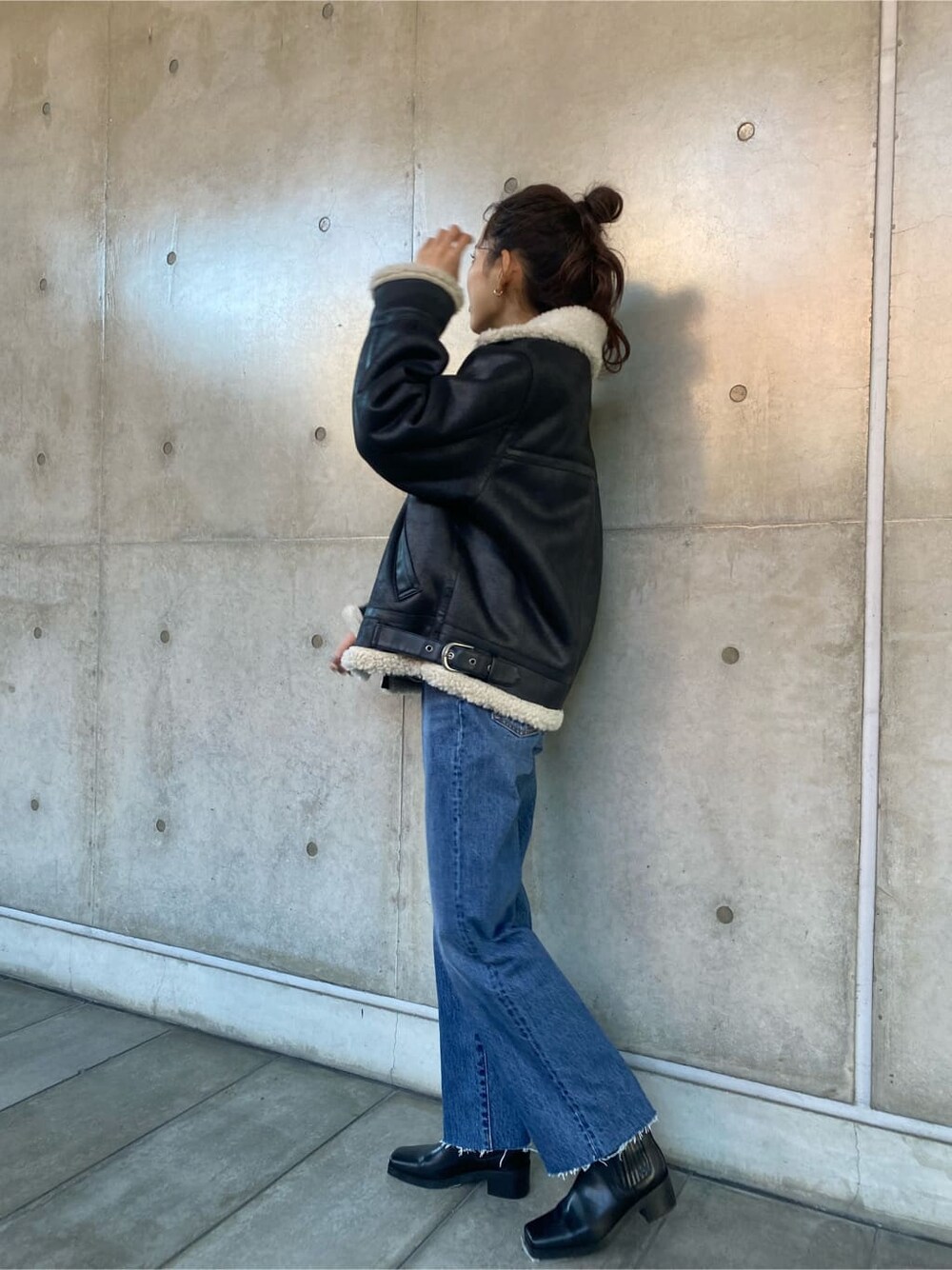ブラック系のブルゾン、ブルー系のデニムパンツ、グレー系のニット/セーターを着用したレディースの秋コーディネートの3枚目の写真