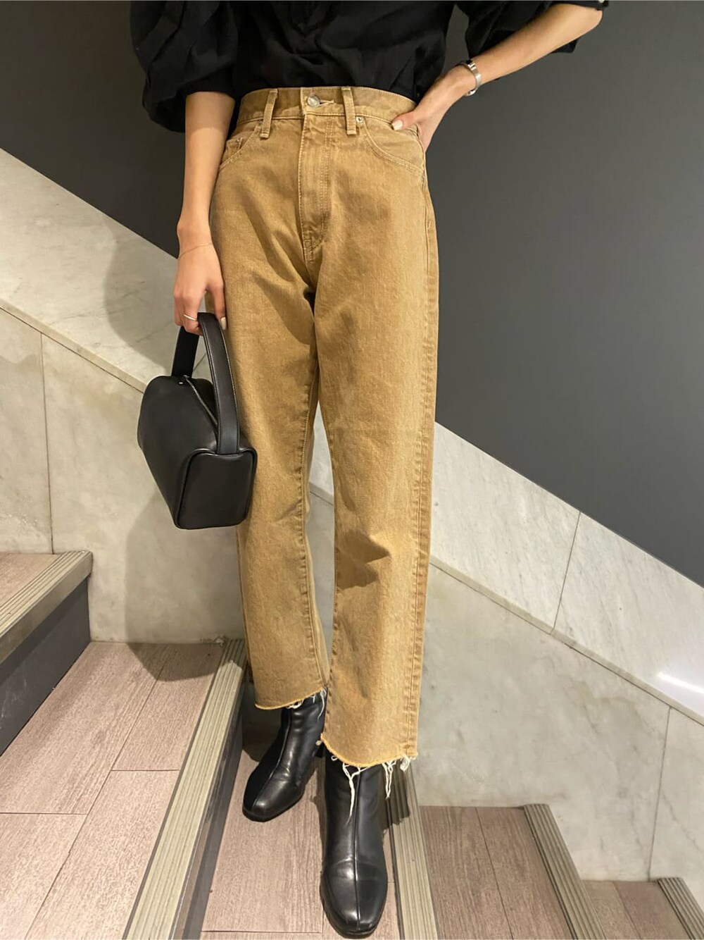 ブラック系のシャツ/ブラウス、ブラック系のハンドバッグ、ベージュ系のデニムパンツを着用したレディースの冬コーディネートの4枚目の写真