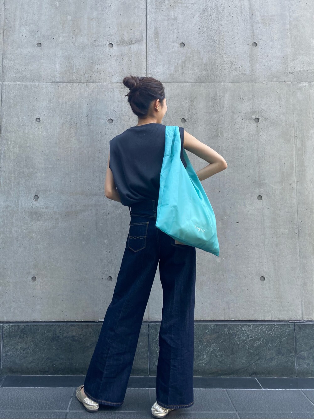 ブルー系のハンドバッグ、ブルー系のデニムパンツ、グレー系のタンクトップを着用したレディースの春コーディネートの3枚目の写真