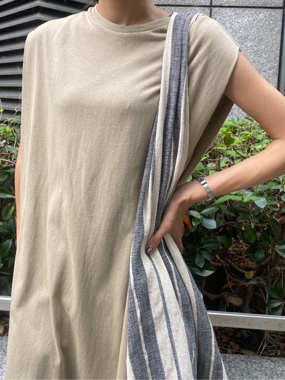 ブラック系のサンダル、ベージュ系のワンピース、ブルー系のデニムパンツを着用したレディースの夏コーディネートの5枚目の写真