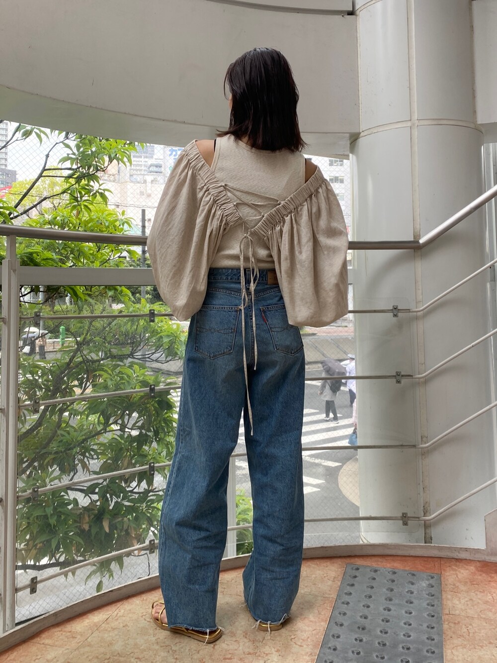 ベージュ系のシャツ/ブラウス、ブルー系のデニムパンツ、ゴールド系のサンダルを着用したレディースの春コーディネートの2枚目の写真